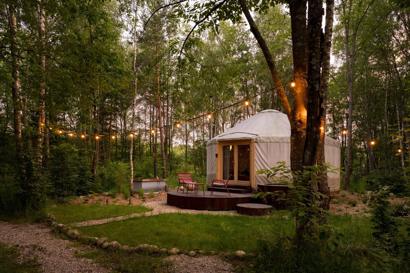 Glamping-Zelt im Wald mit Lichterkette am Abend Getty