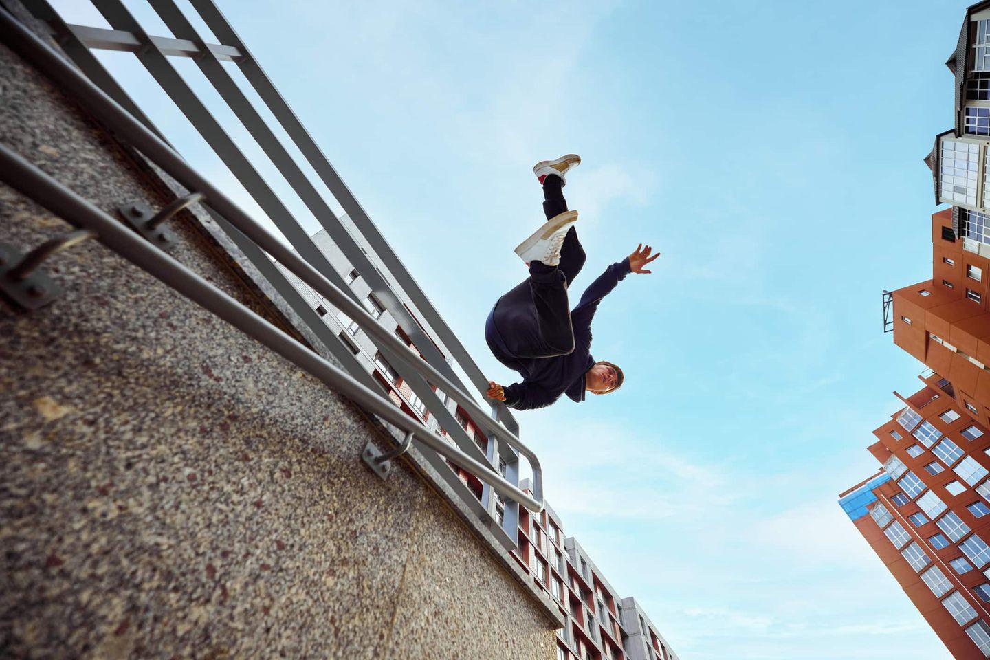 Sportler springt beim Parkour rückwärts von einem Geländer in der Stadt. Getty