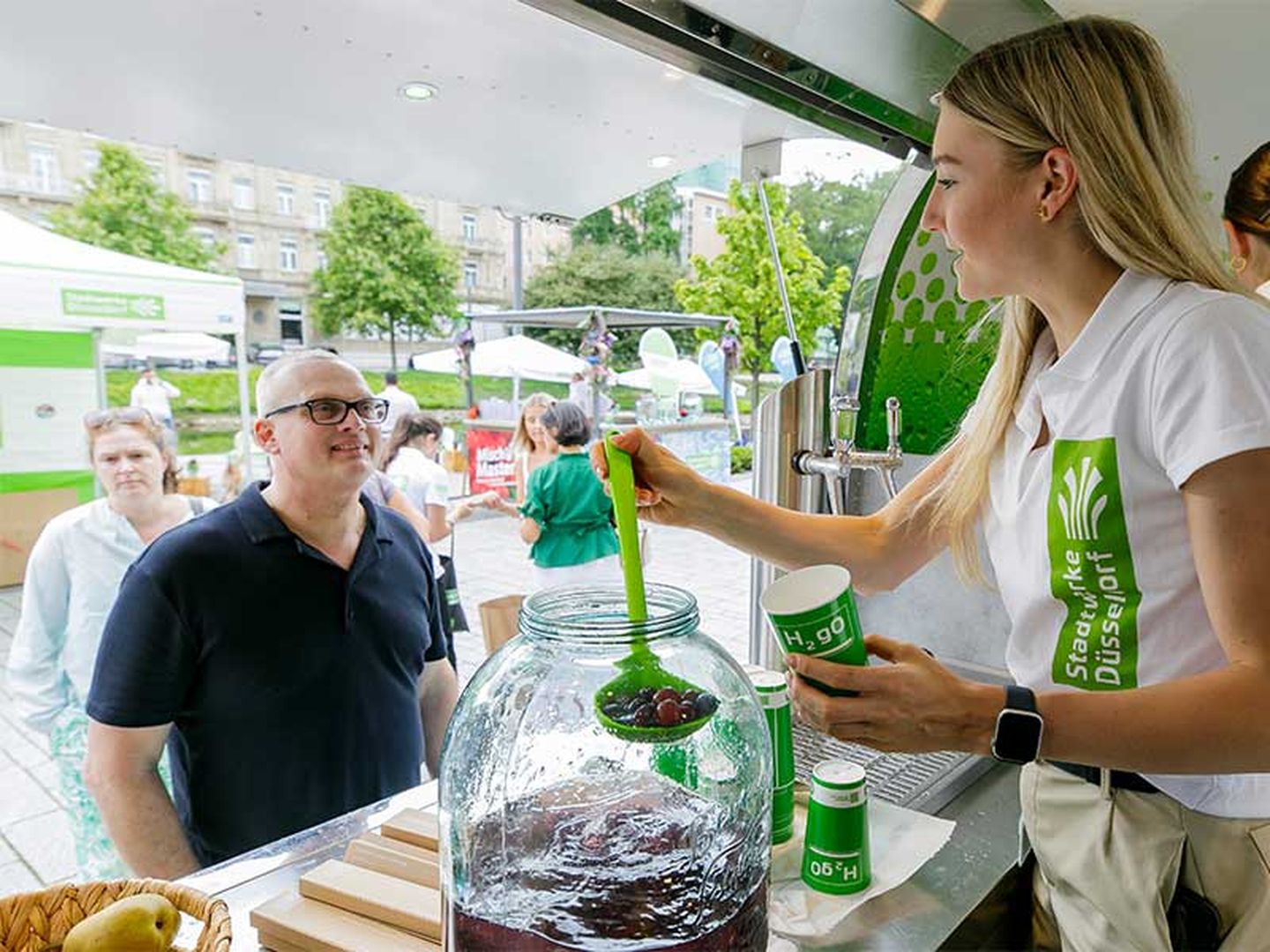 Ein Gast erhält fruchtiges Trinkwasser aus dem Wasserwagen