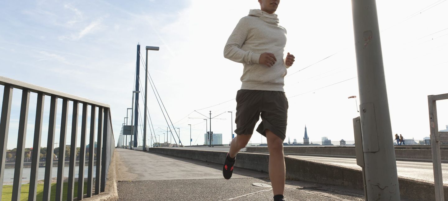 Vier Menschen joggen am Rhein entlang