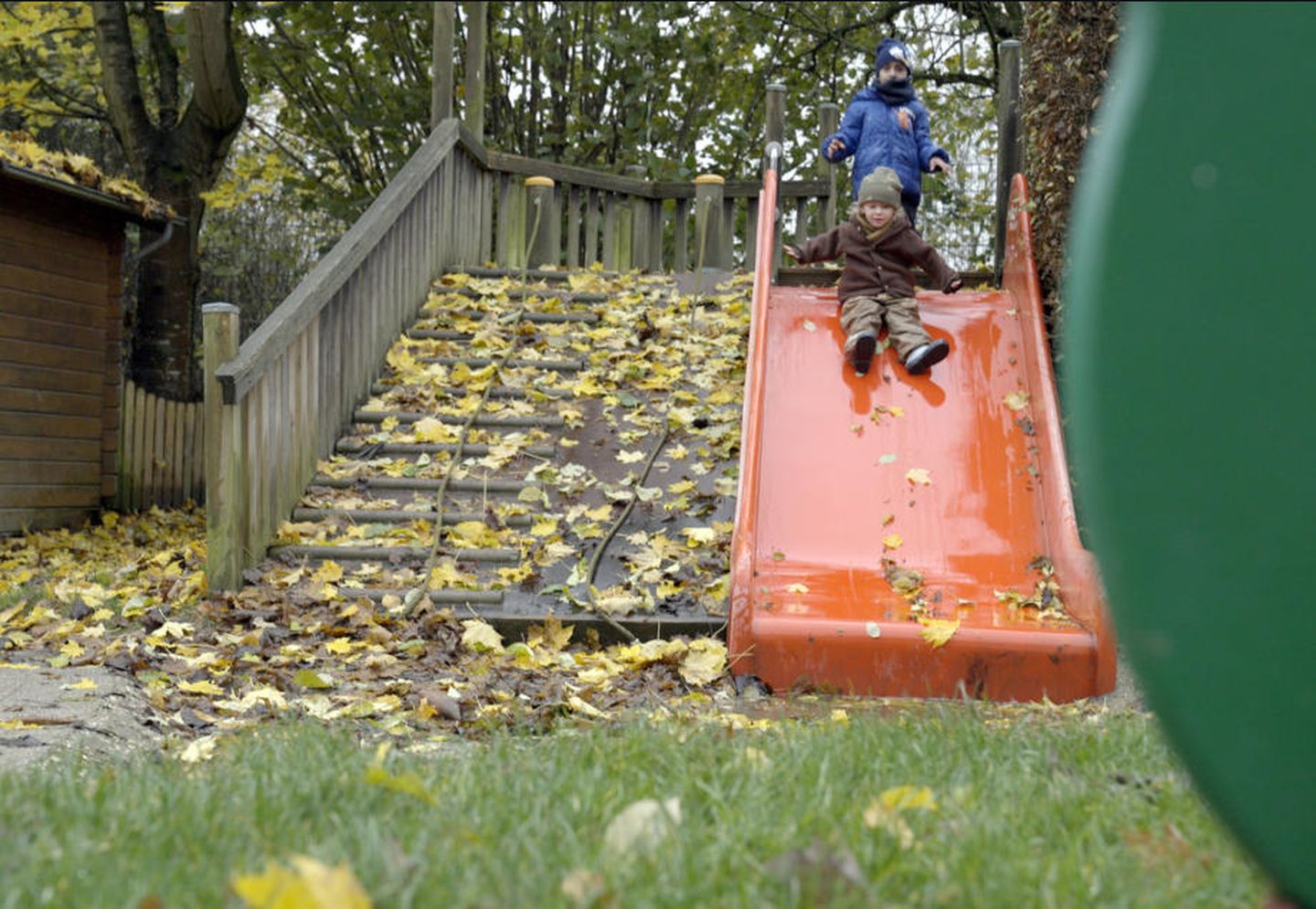 Kinder spielen an einer roten Rutsche.
