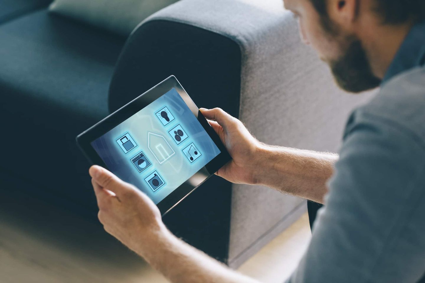 Mann bedient Smart-Home-System auf Tablet zur Steuerung von Haushaltsgeräten. Getty