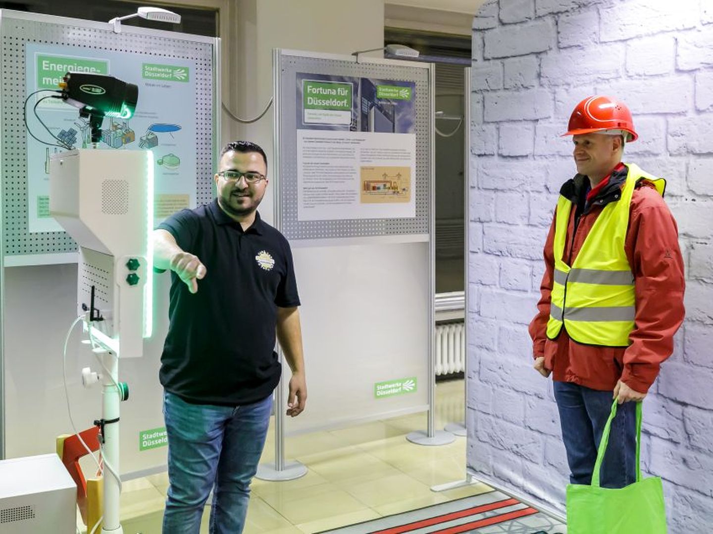 Besucher mit Helm und Warnweste an einem Ausstellungsstand der Stadtwerke Düsseldorf. © Stadtwerke Düsseldorf © Stadtwerke Düsseldorf