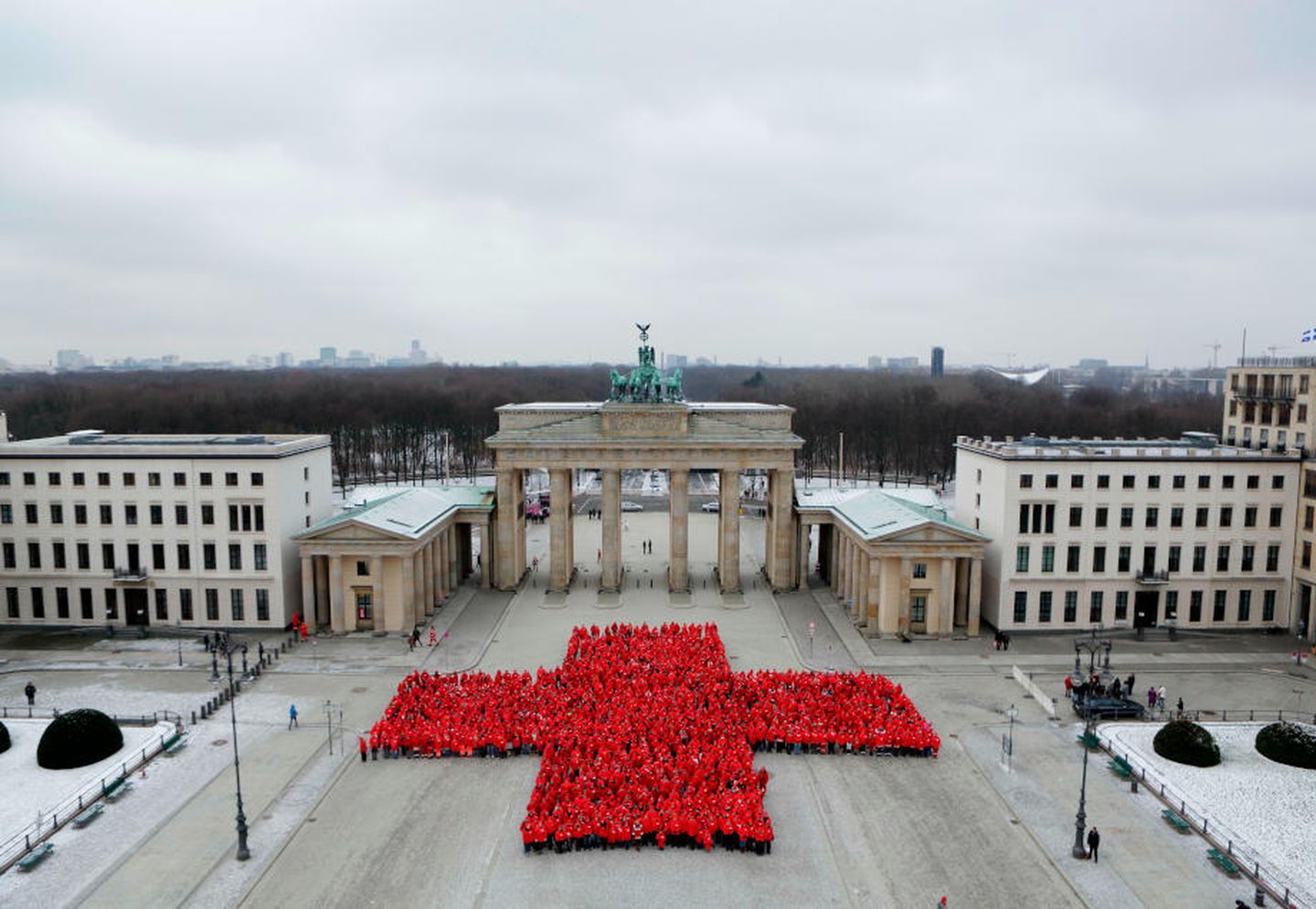 Luftaufnahme von Mitarbeiter:innen des DRK, die sich zu einem roten Kreuz formieren.