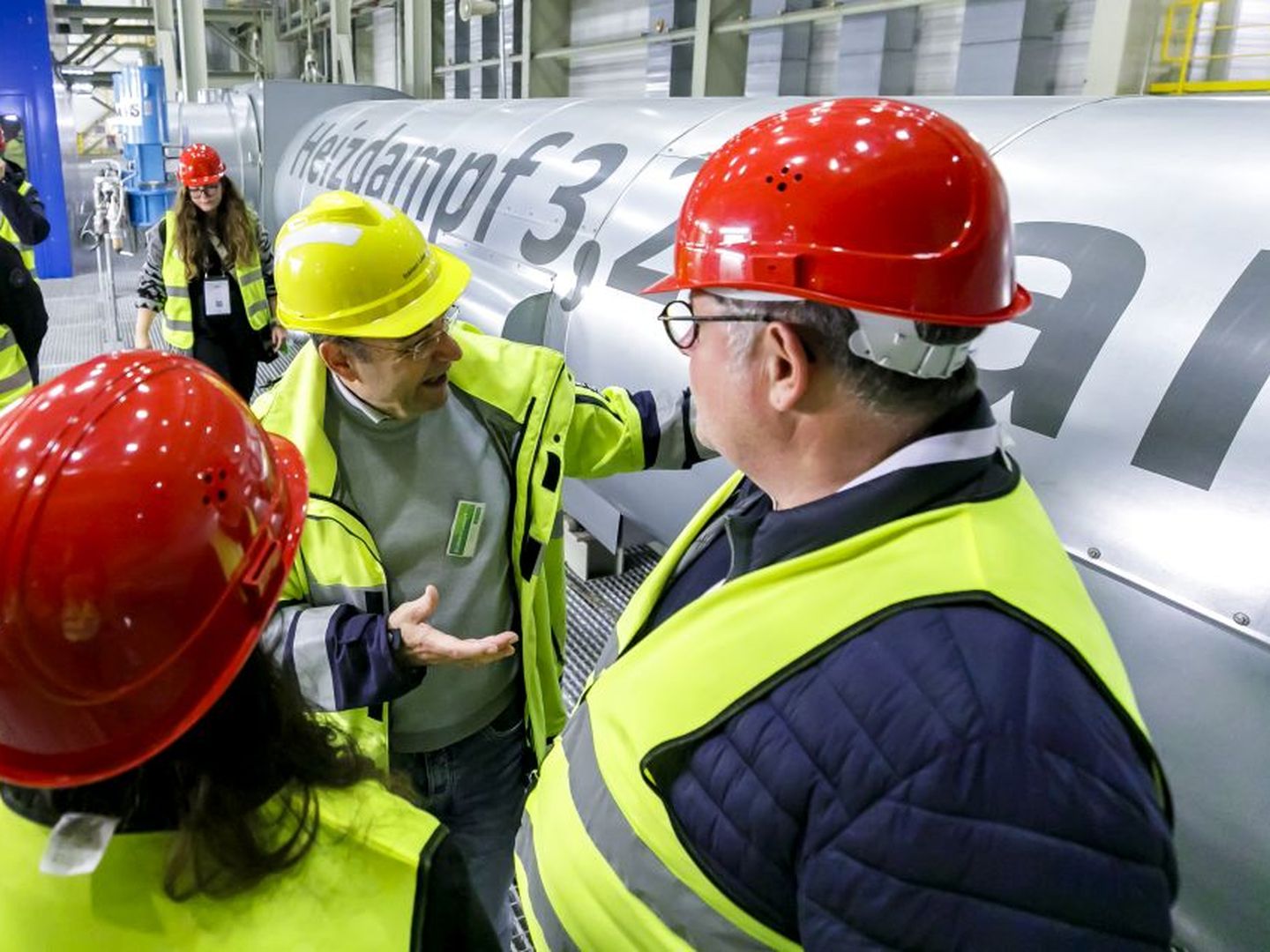 Mitarbeiter der Stadtwerke Düsseldorf erläutert Besucher:innen eine große Industrieanlage. © Stadtwerke Düsseldorf