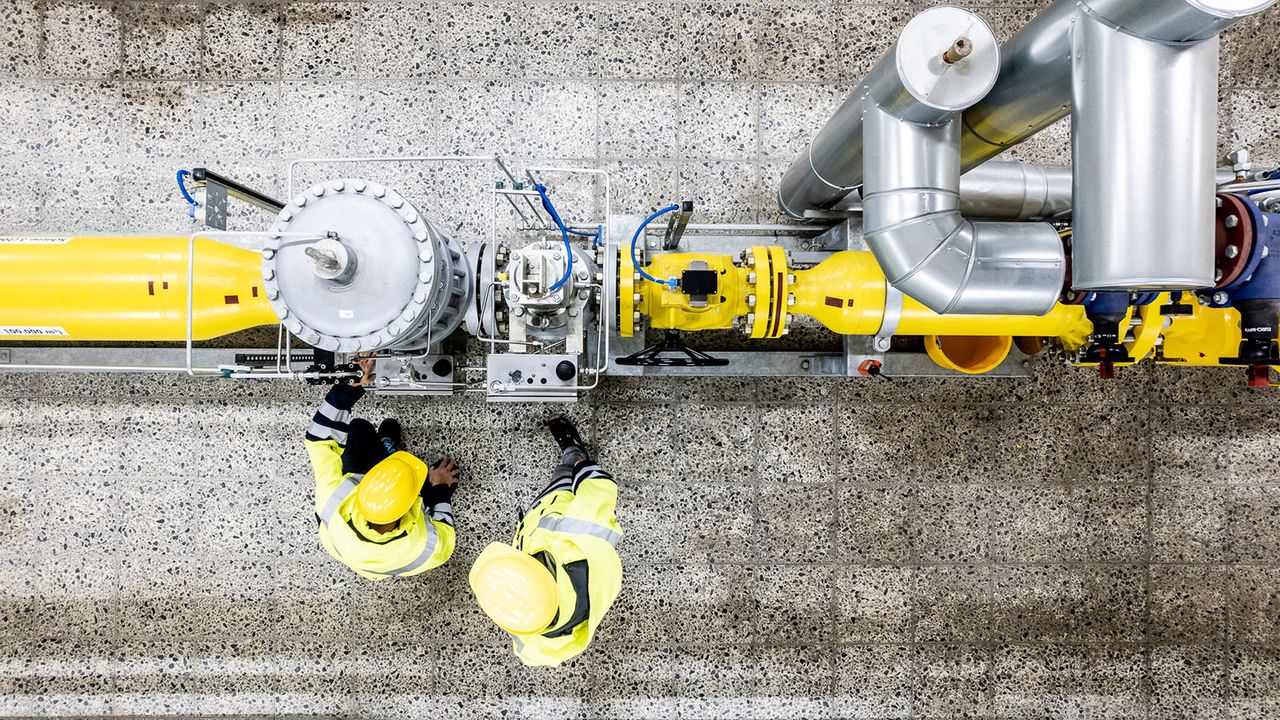 Bild von oben und zwei Mitarbeiter stehen vor Maschine