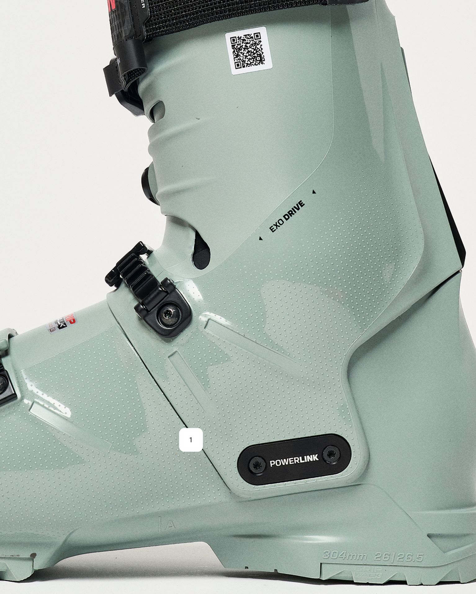 Close-up of a grey ski boot featuring advanced buckles, "EXO DRIVE" and "POWERLINK" labels, showcasing modern mountain sports design.