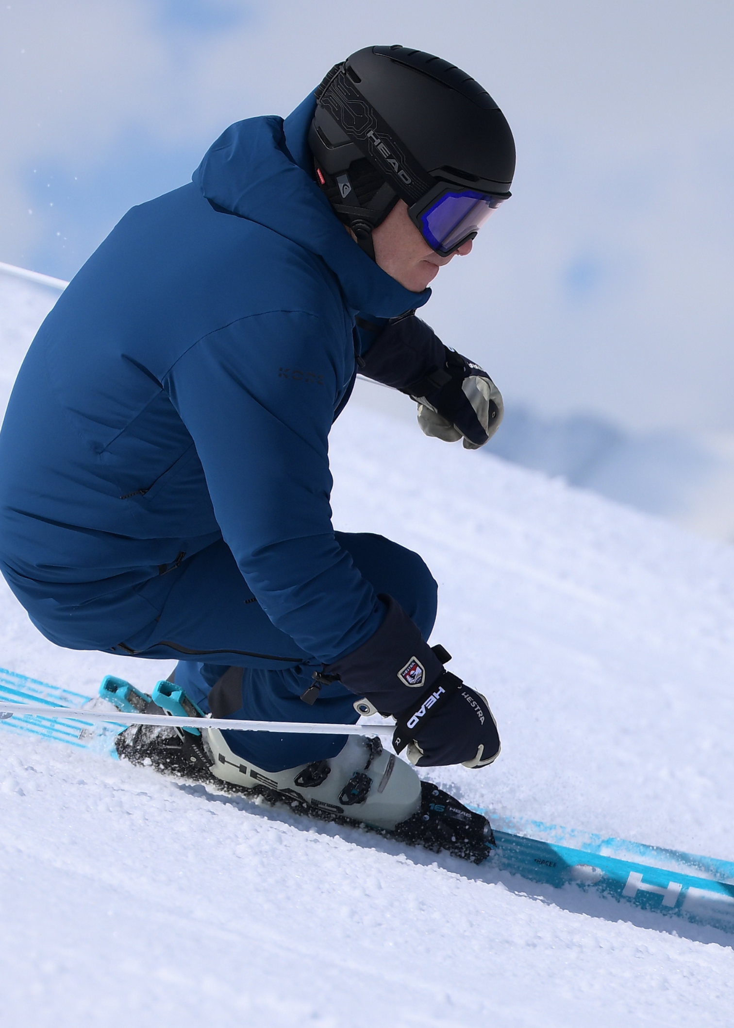 A skier in blue gear and a black helmet expertly carves down a snowy mountain slope, showcasing precision and skill.