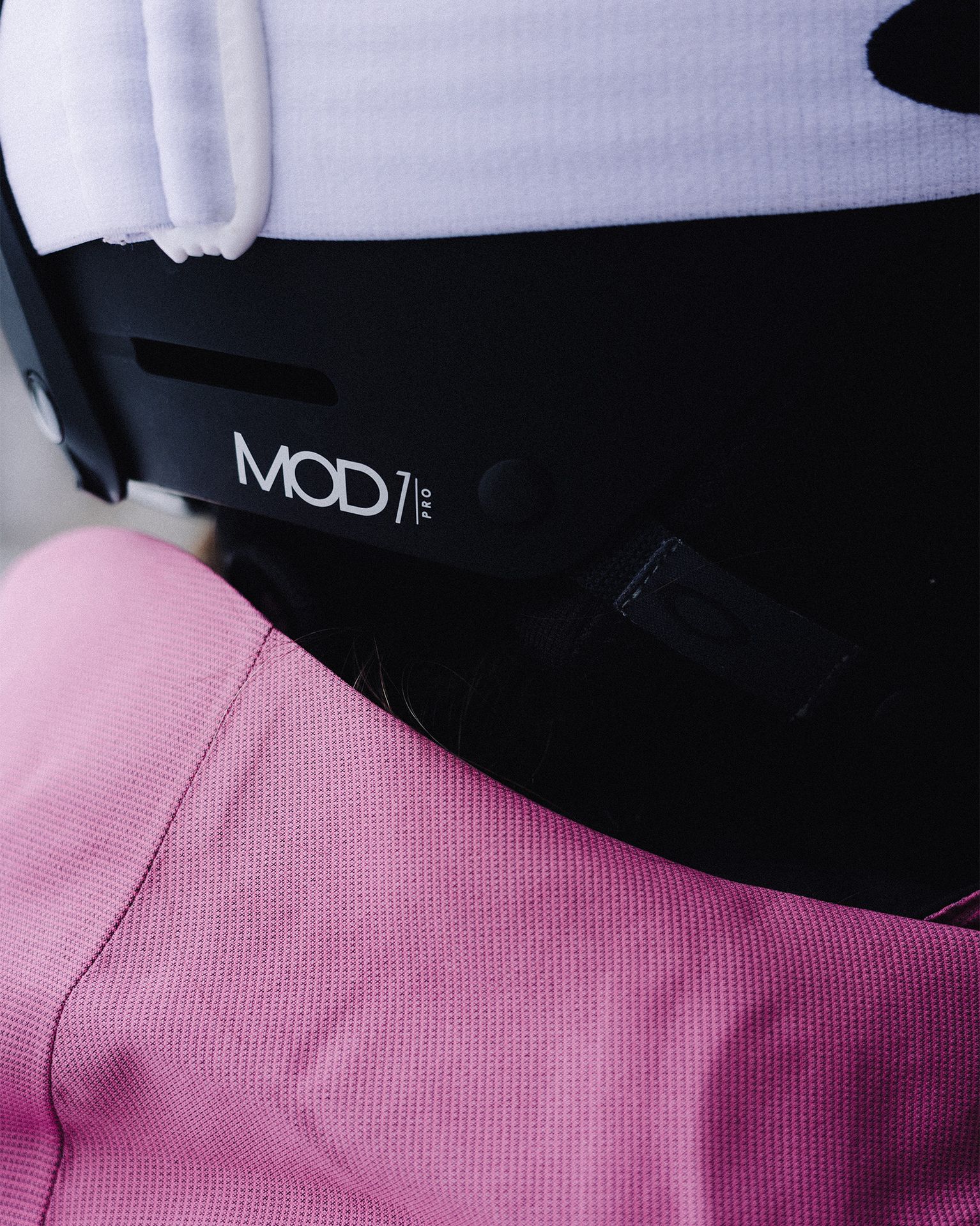 Close-up of a MOD1 Pro helmet and pink textured fabric, showcasing the helmet's branding and design details.