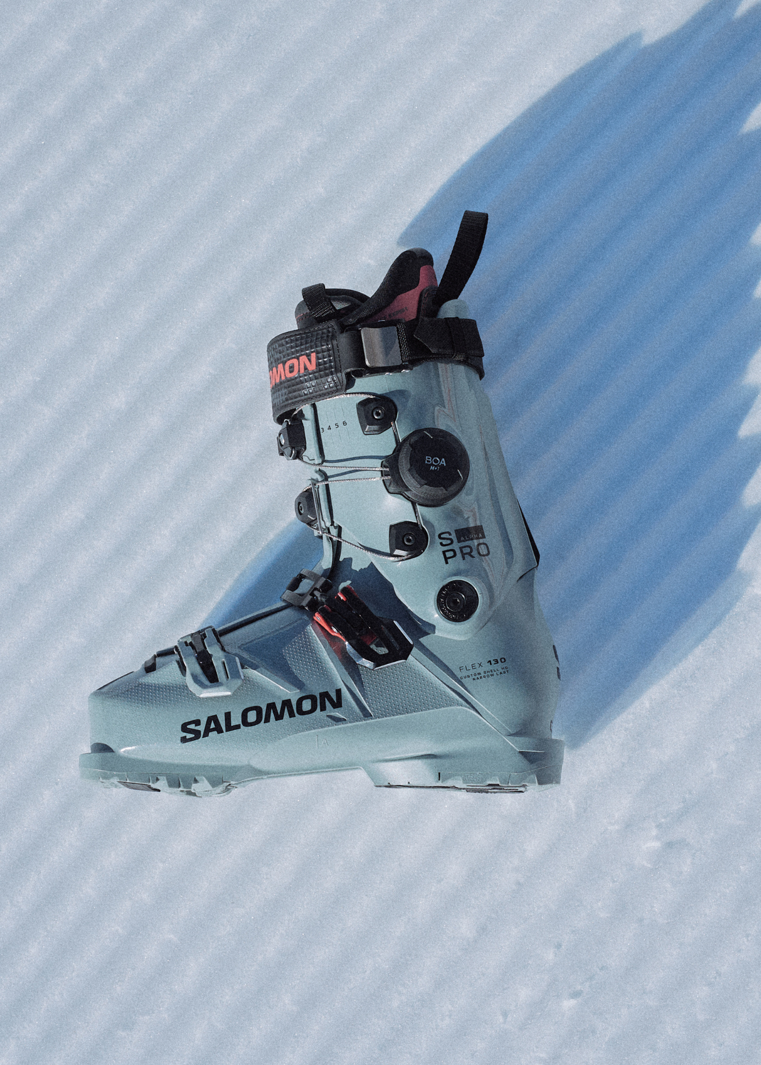 Salomon ski boot on textured snow, showcasing buckles and branding. Perfect for mountain sports enthusiasts seeking quality gear.