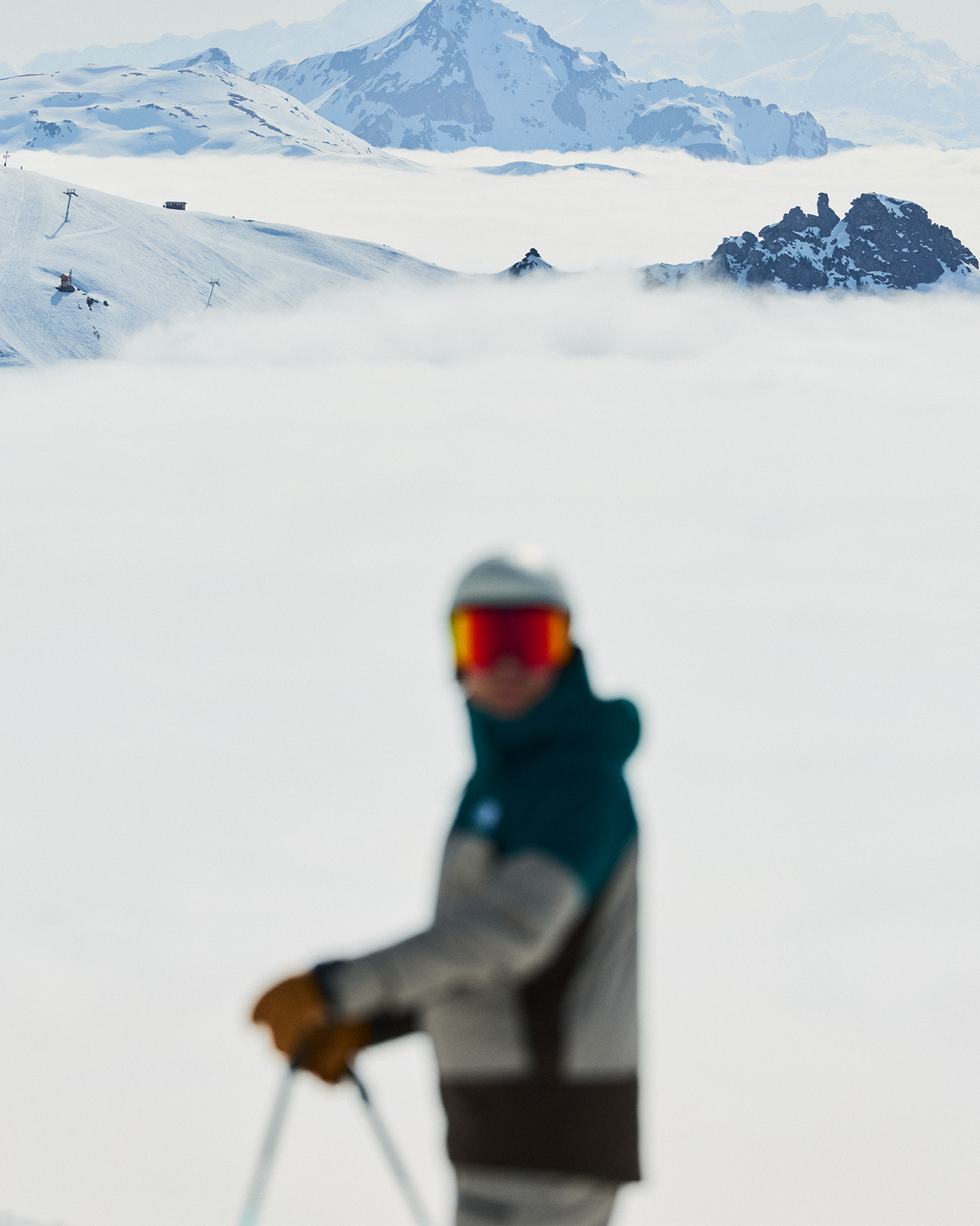 Skier in focus, dressed in high-quality gear, with snow-capped peaks in the distance, creating an inspiring alpine backdrop.
