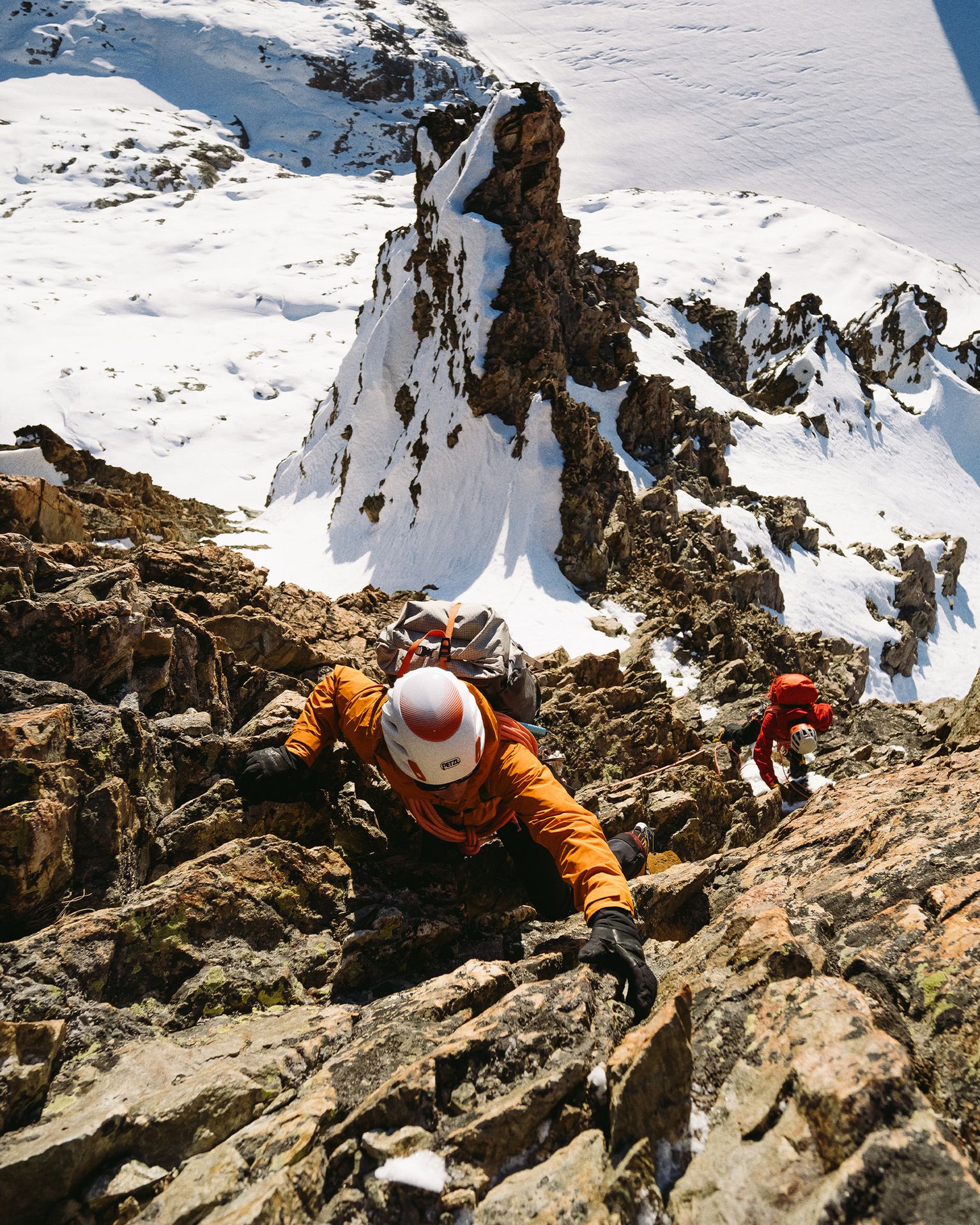 Climber wearing orange climbing gear ascending rocky terrain