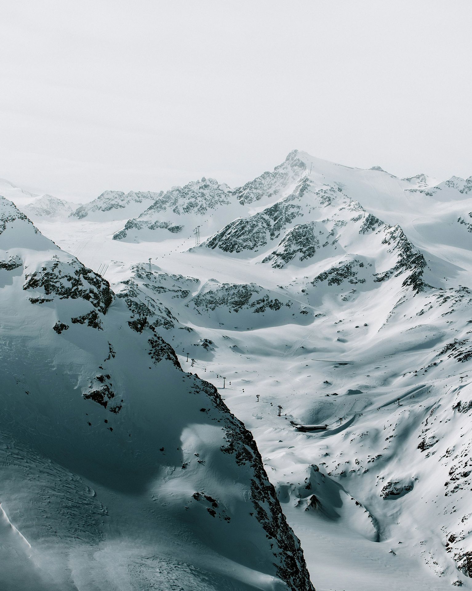 Snow-covered mountain range with jagged peaks under a cloudy sky, creating a serene and majestic winter landscape.
