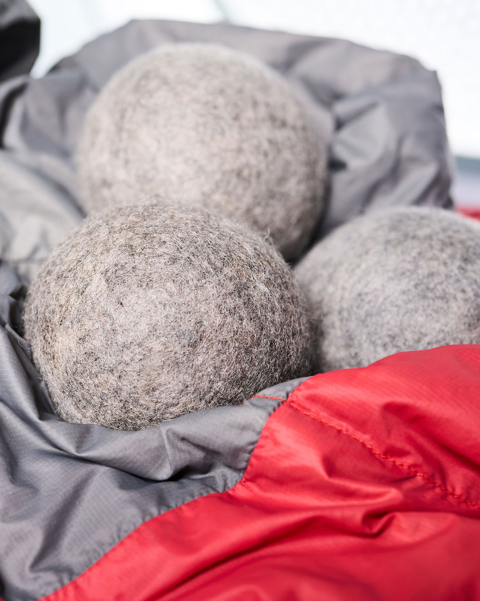 Three gray wool dryer balls nestled in a red and gray fabric.