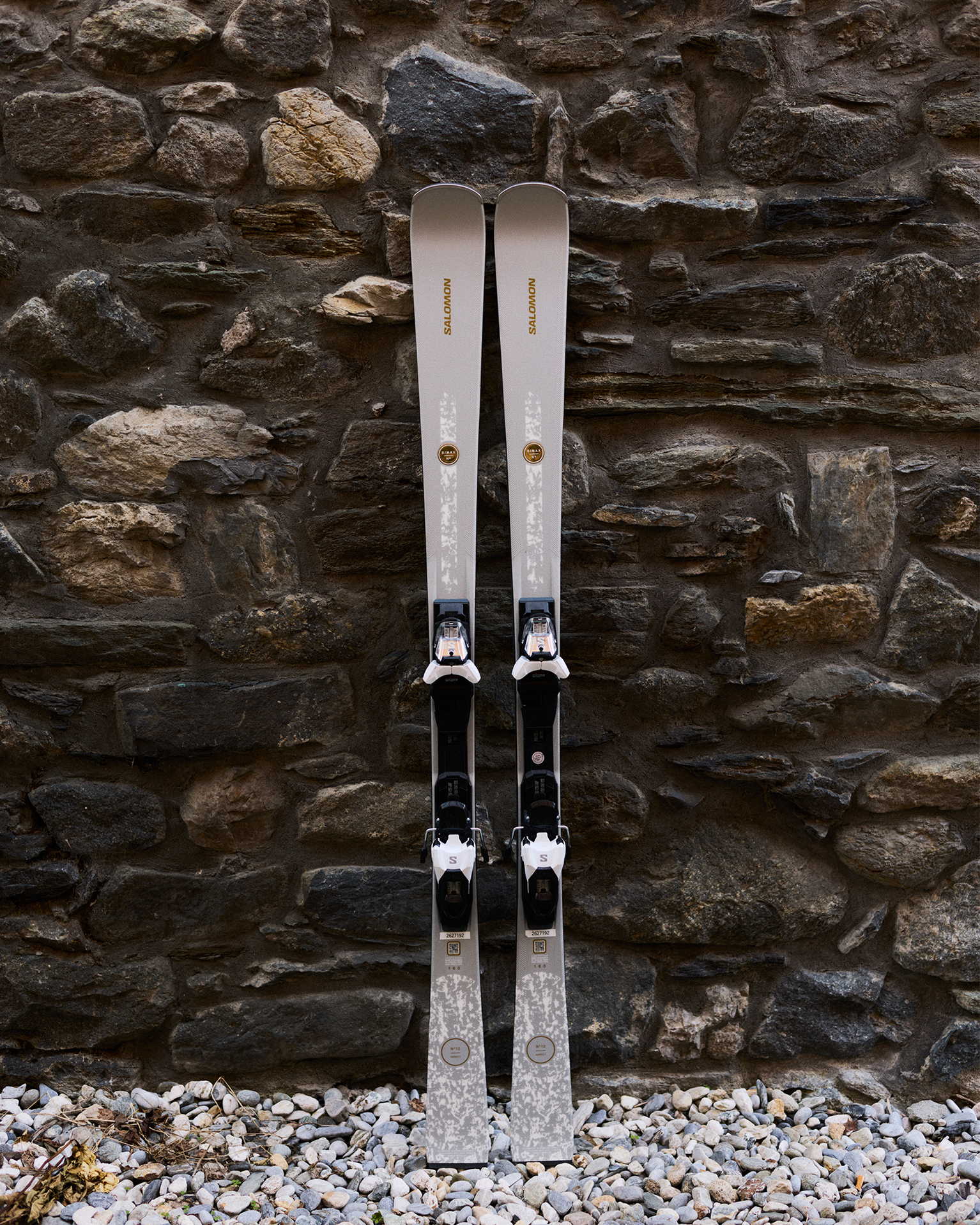 Pair of skis set against a rustic stone wall, designed for adventurous mountain sports enthusiasts.