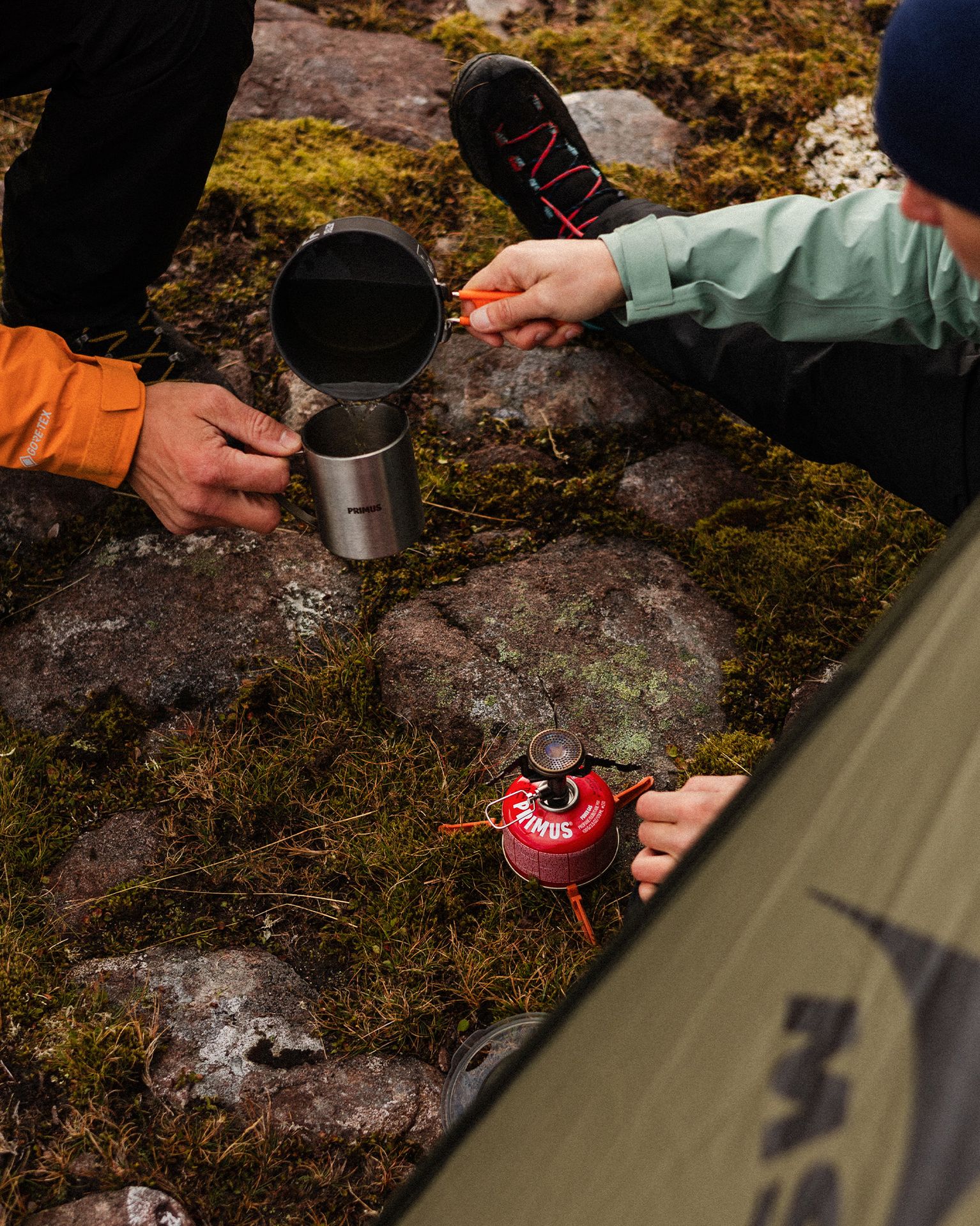 Two campers sat by a tent and camping stove