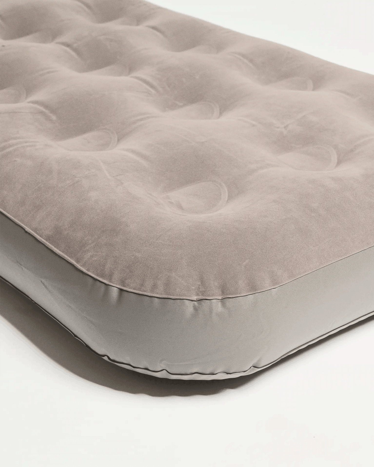 Grey inflatable mattress with a soft, tufted surface. Ideal for camping.