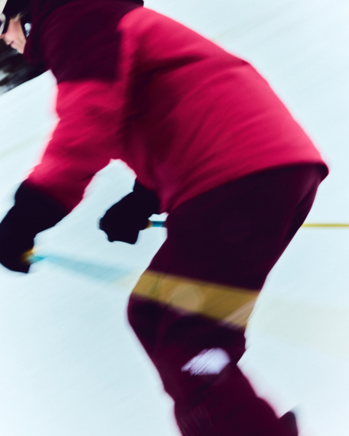 Person skiing down a snowy slope, wearing a red jacket and black gloves, captured in motion.