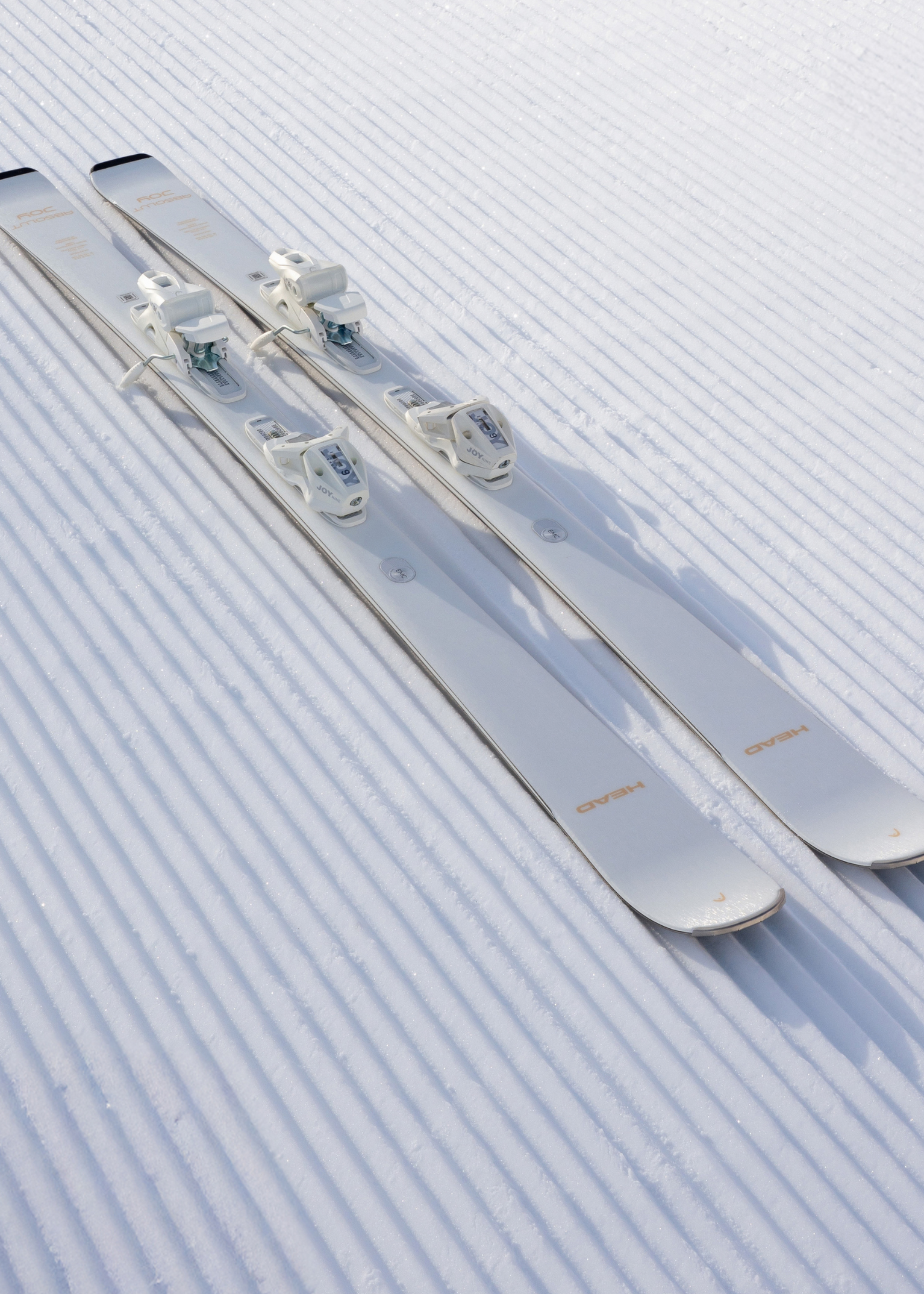 A pair of Head e.Absolut Joy Skis lie on freshly groomed snow