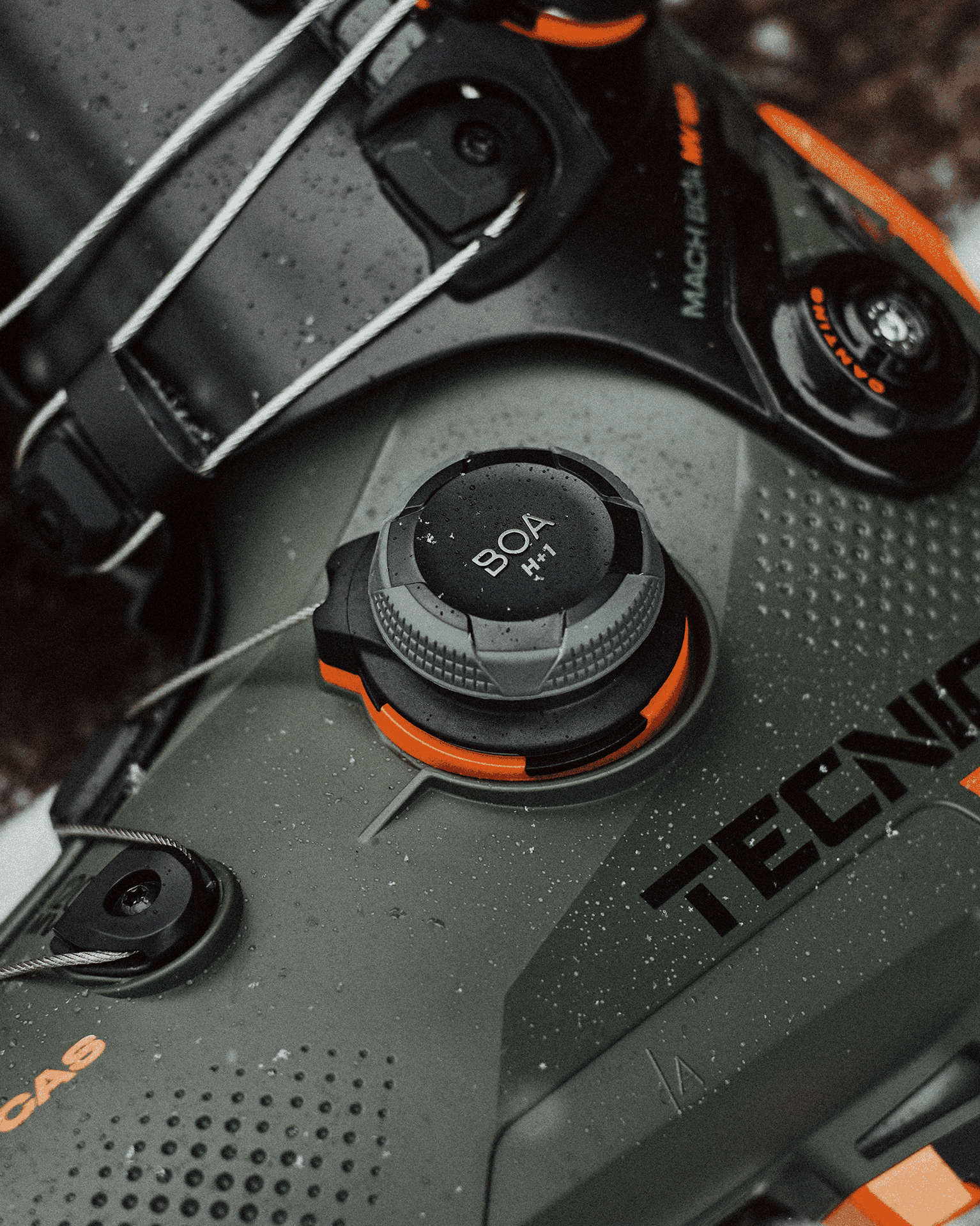 Close-up of a Tecnica ski boot featuring a BOA dial system for precision fit, showcasing durable design, with visible raindrops on the surface.