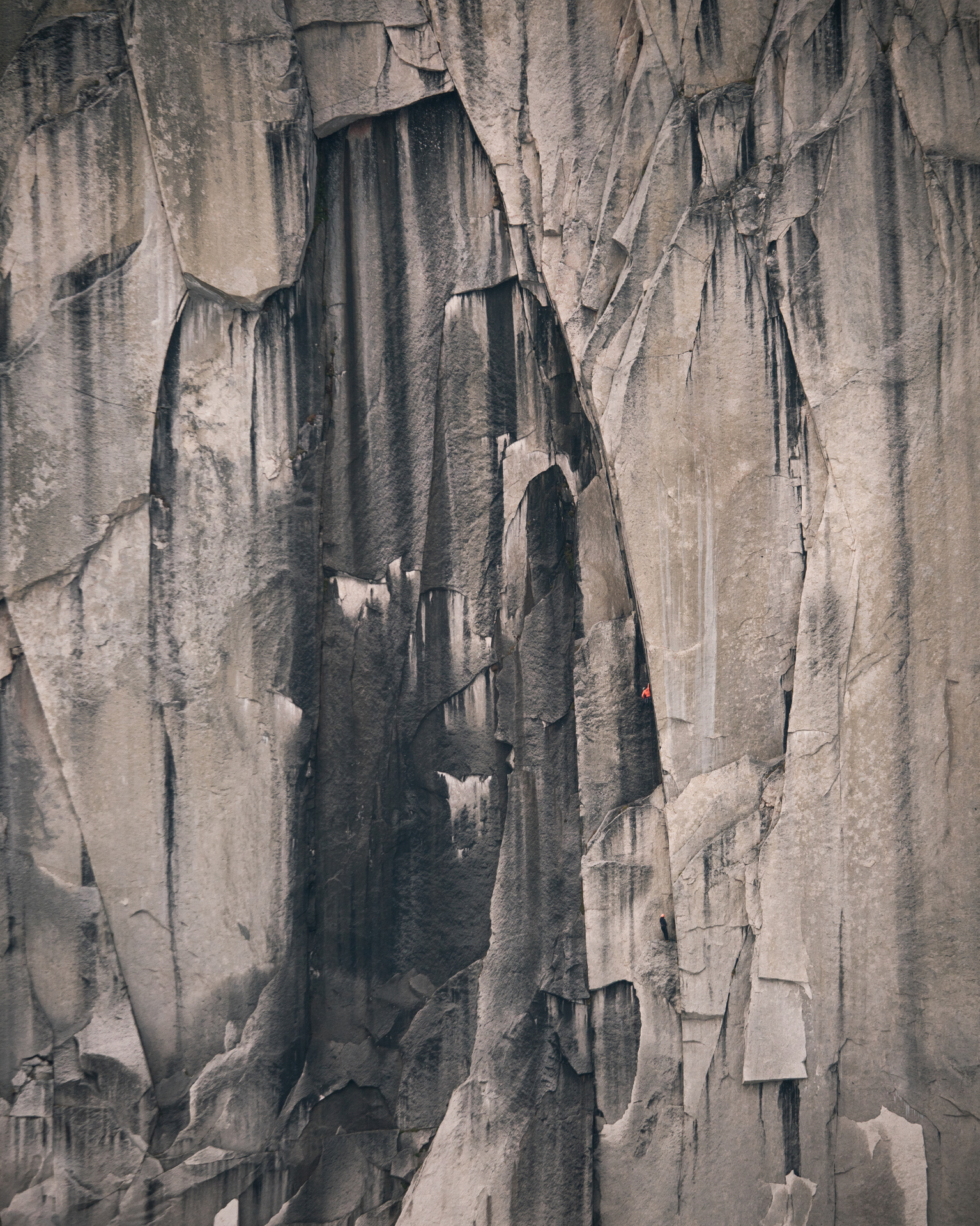 Close-up of a rugged rock face with textured vertical lines and crevices, showcasing natural geological formations.