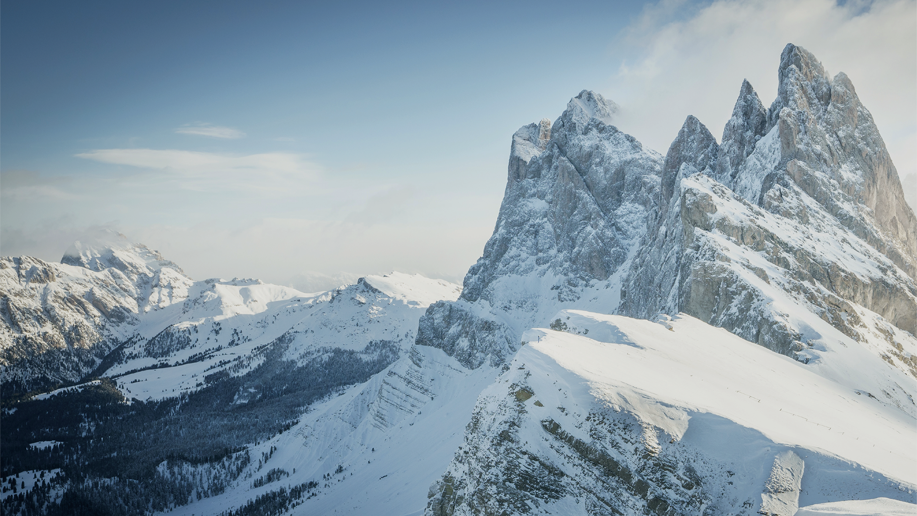 Snow-covered mountain peaks under a clear blue sky, highlighting rugged terrain.