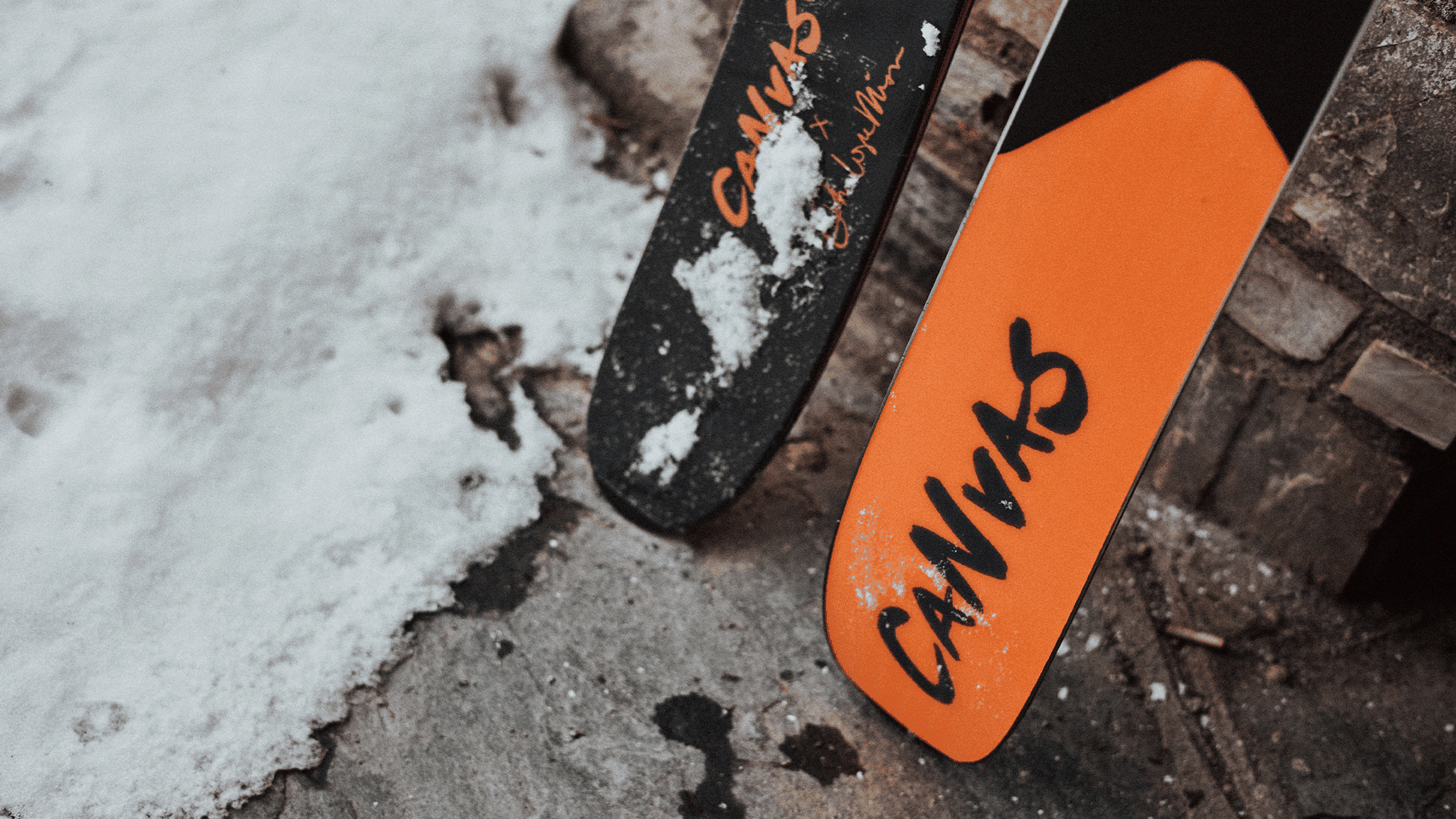Close-up of two skis with snow on them. The ski tips are marked with the word "Canvas" in bold lettering.