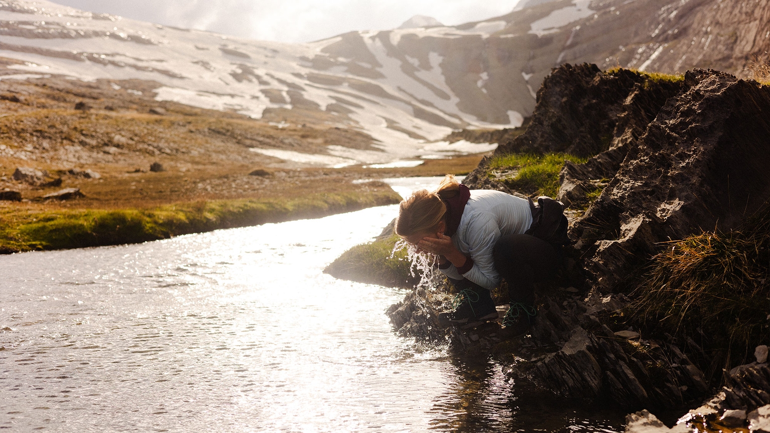 camper washing their face in the river