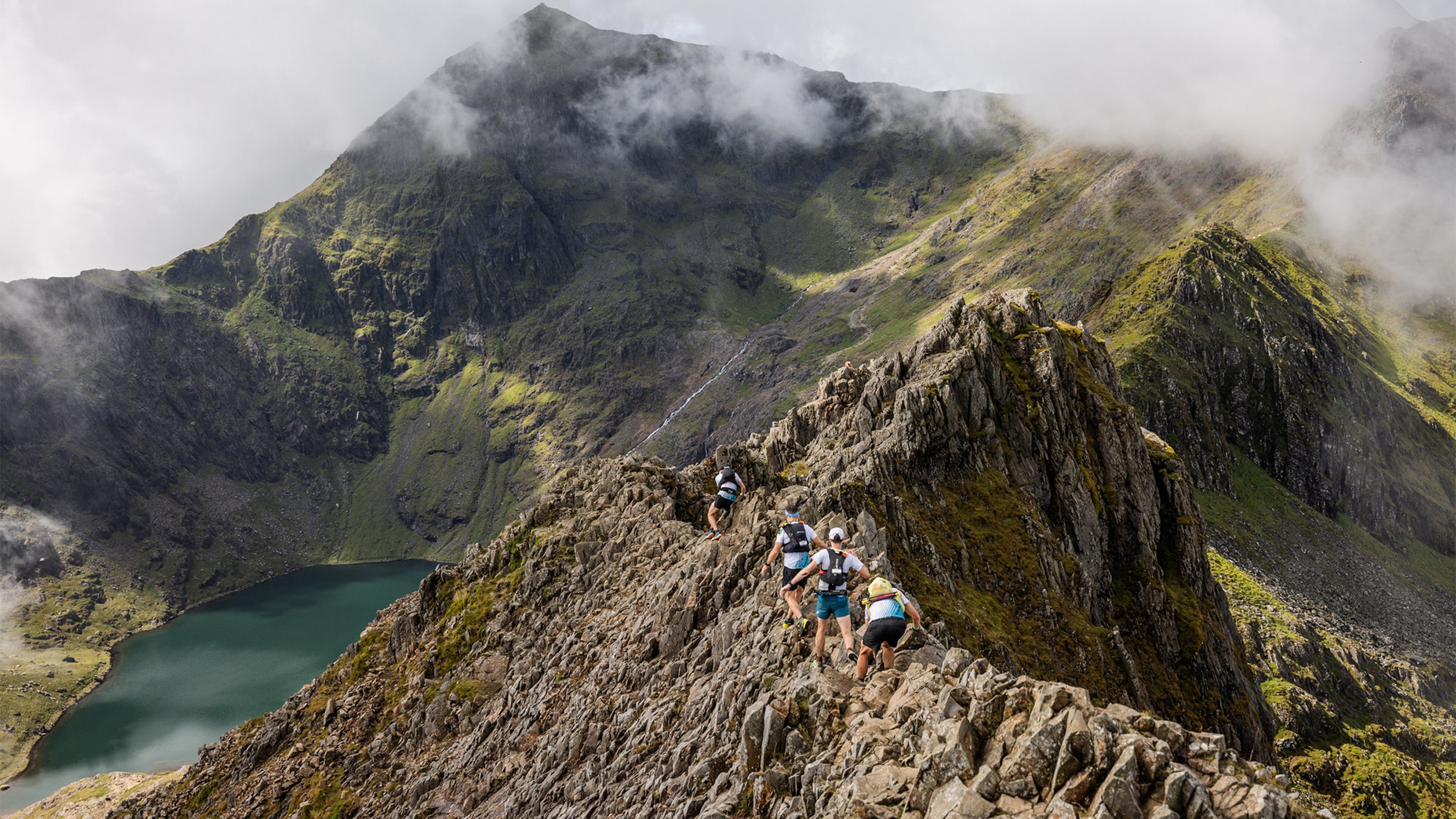 Landscape image of a group of trail runners running along a ridge