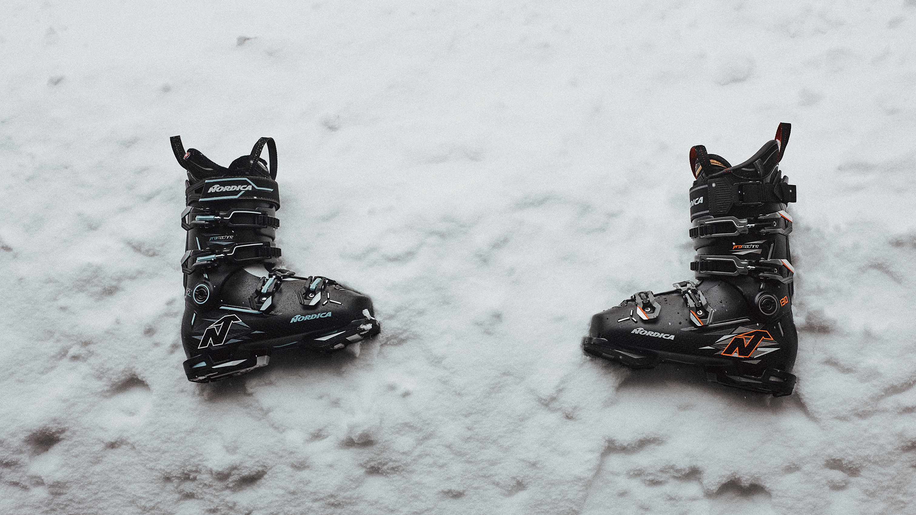 Pair of black ski boots resting on fresh snow, featuring heavy-duty buckles and durable design for cold-weather sports.