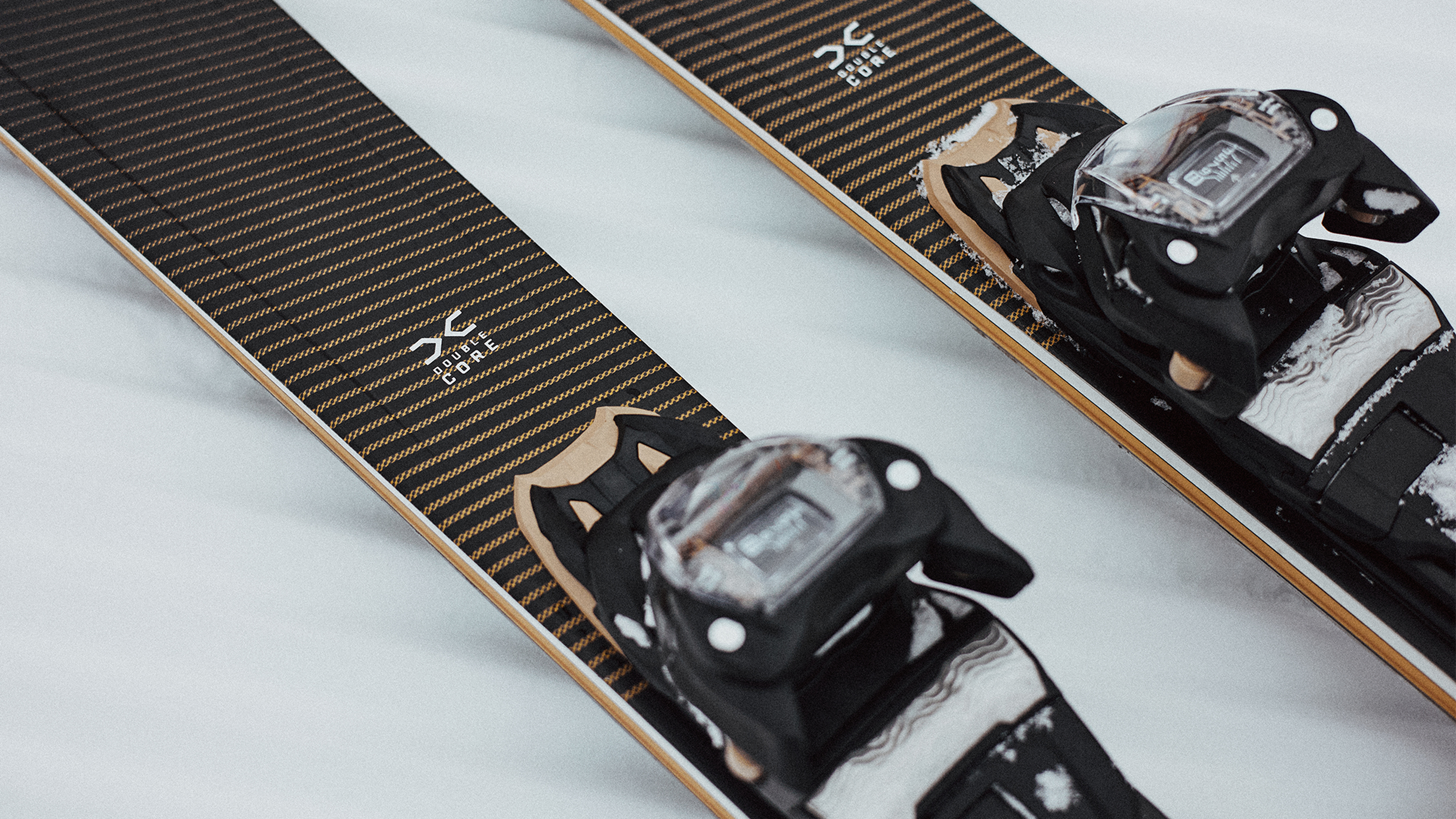 Close-up of high-quality skis with bindings on snow, showcasing intricate design and robust construction for serious mountain sports.