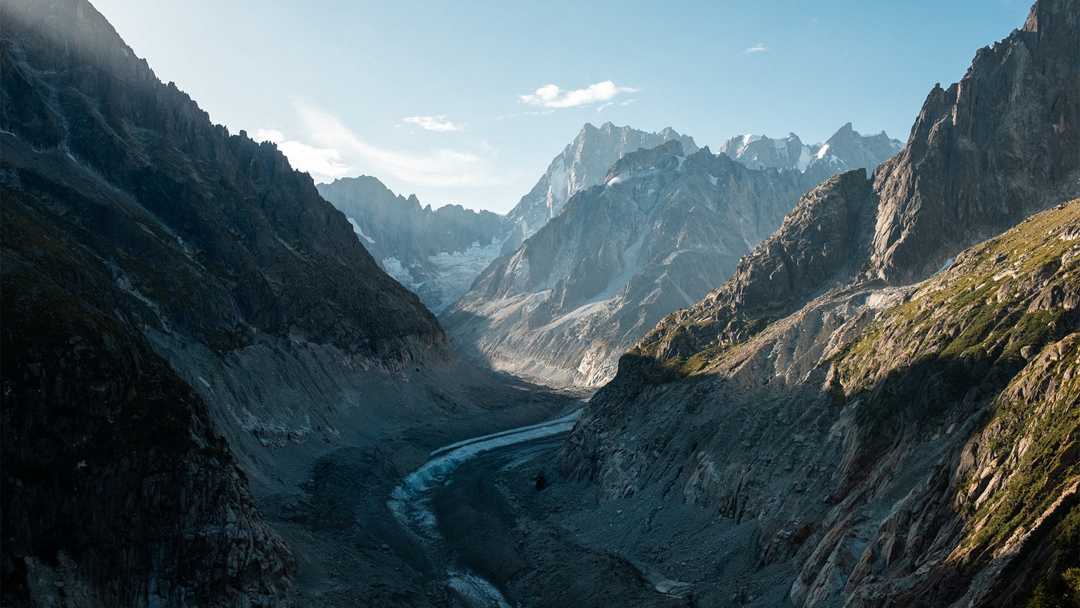 Stunning mountain landscape with rocky peaks and a winding river under a clear blue sky.