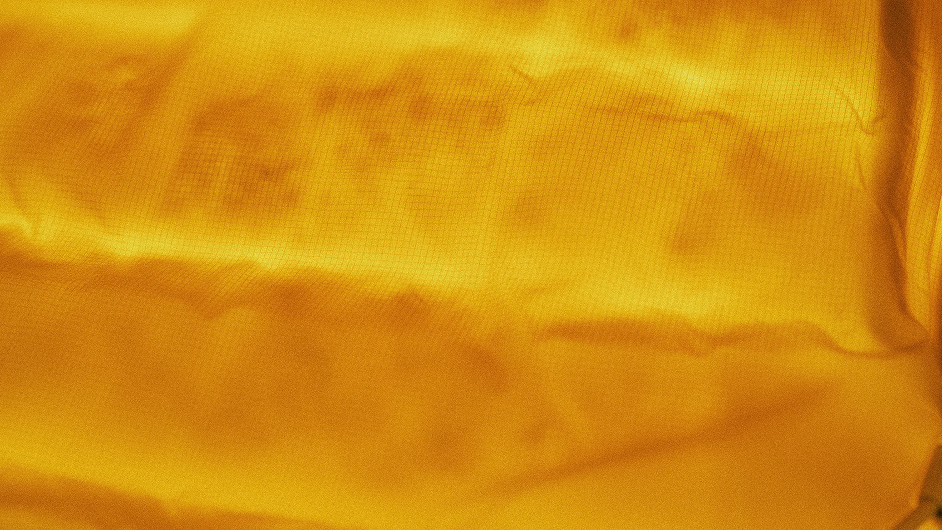 Close-up view of a bright yellow textured fabric with subtle waves and wrinkles.