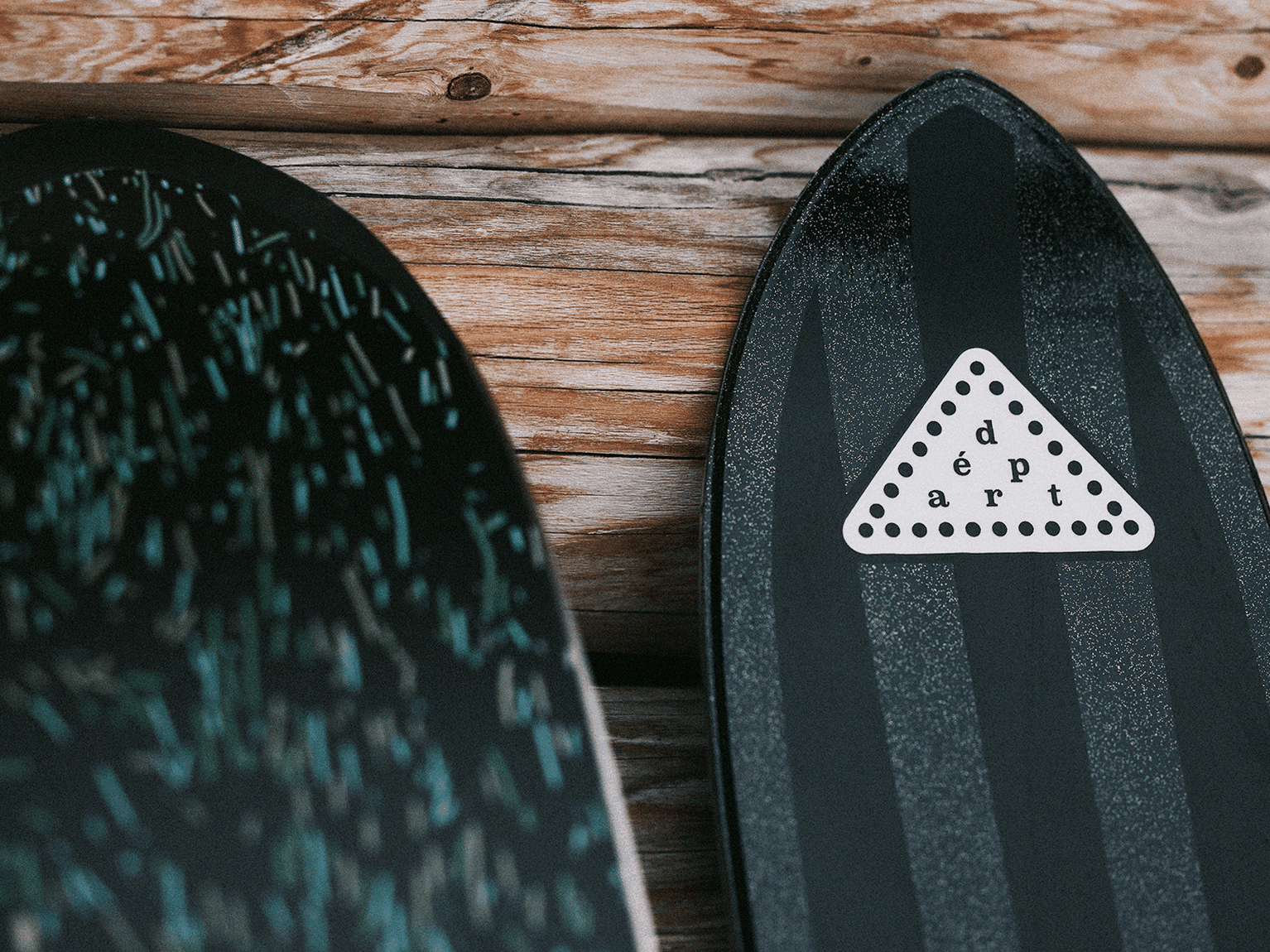 Close-up of skis with unique designs, resting against a wooden background.
