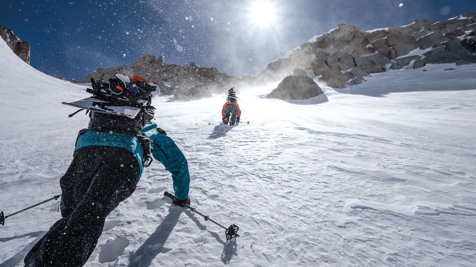 People in patagonia clothing climbing up snowy hill