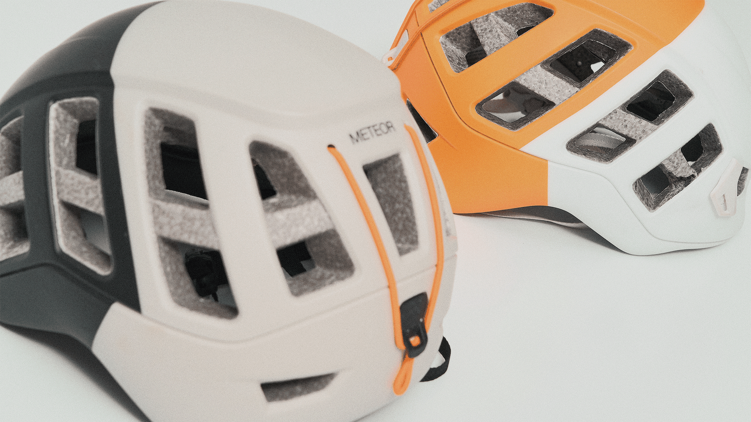 Two climbing helmets in beige and orange.