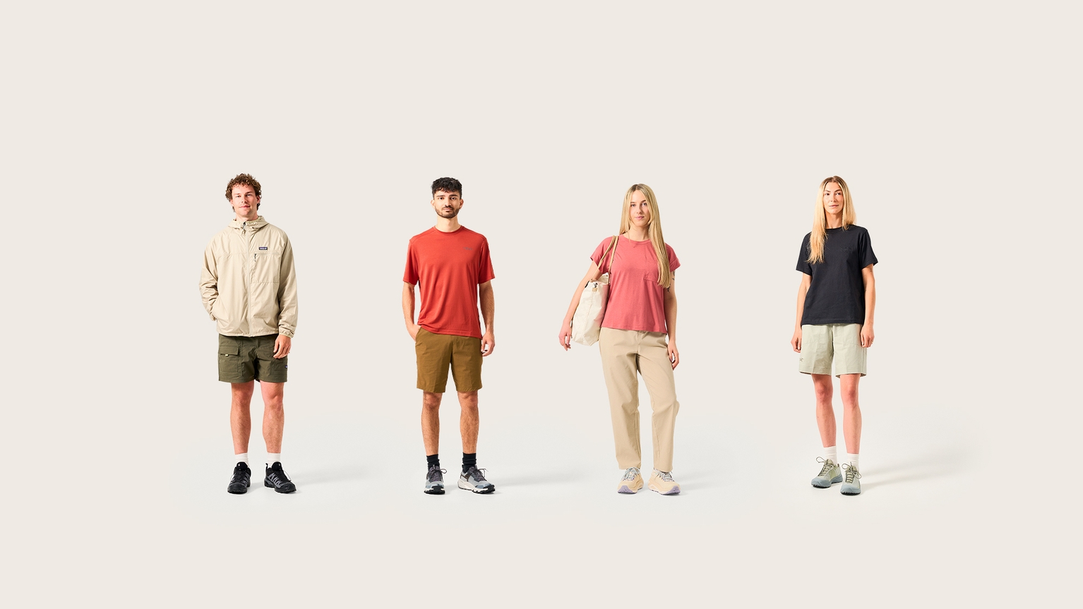 Four people standing in casual outdoor wear against a plain background, showcasing mountain sports clothing.