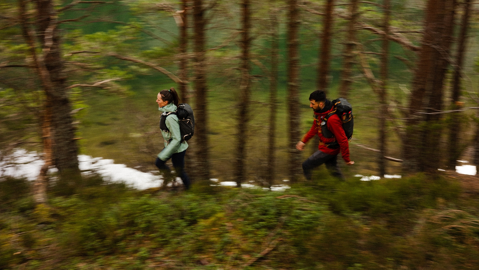 Two people fastpacking through woodland