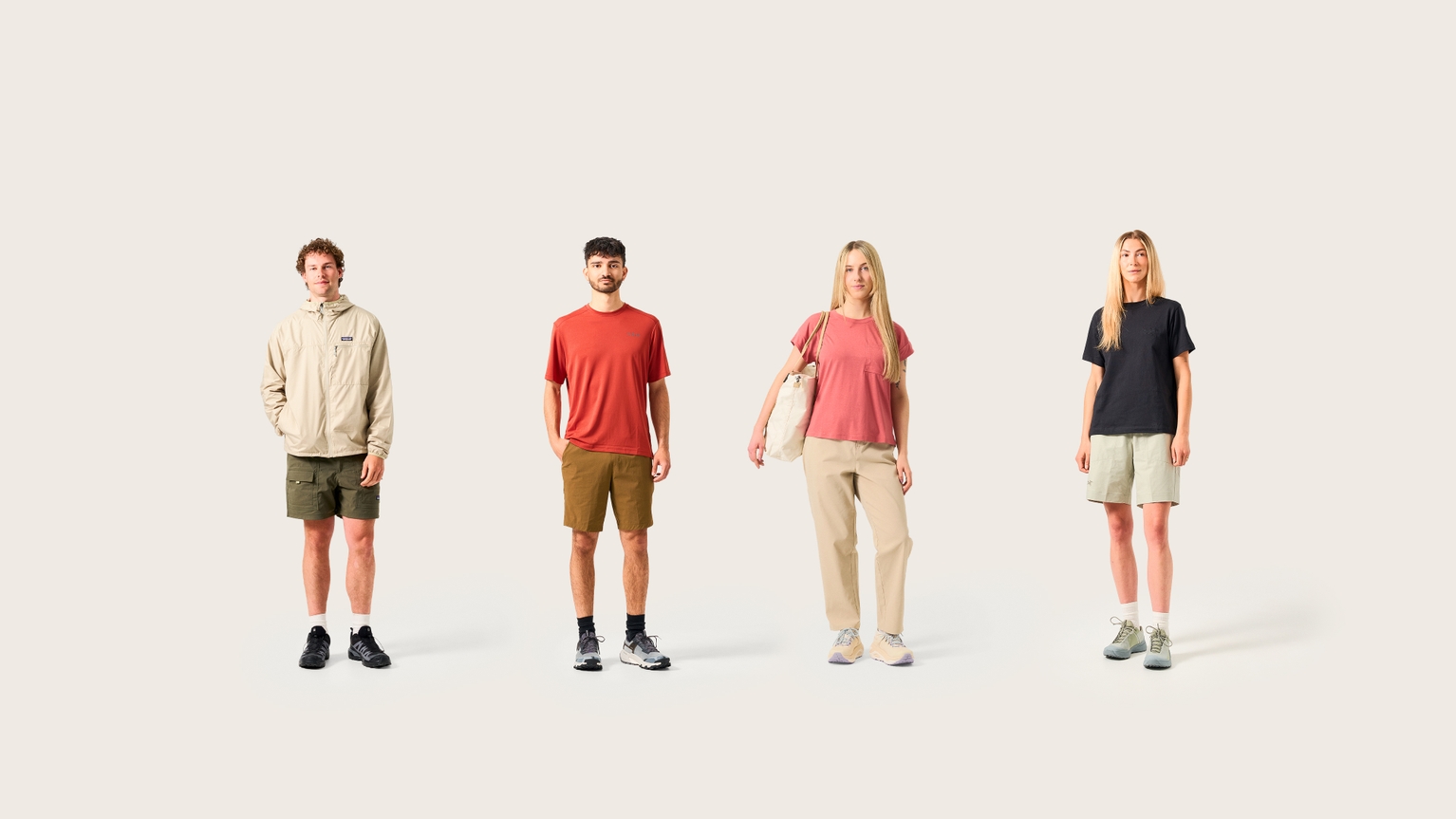 Four people wearing casual outdoor clothing, standing against a plain backdrop.