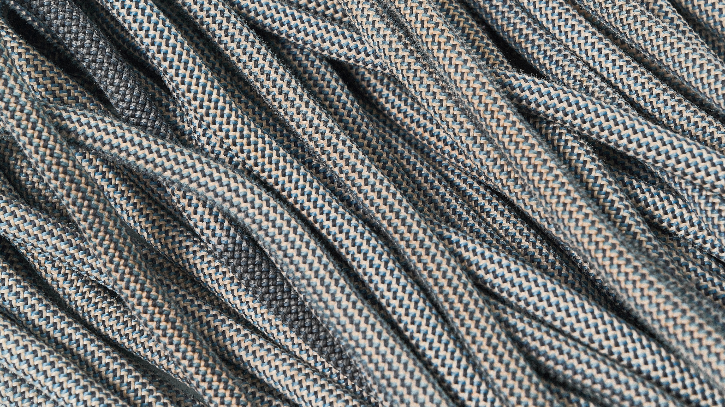 Close-up of coiled grey climbing ropes with a textured weave.
