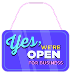A blue sign with "Yes, we're open for business" in bold text, hanging by pink strings.