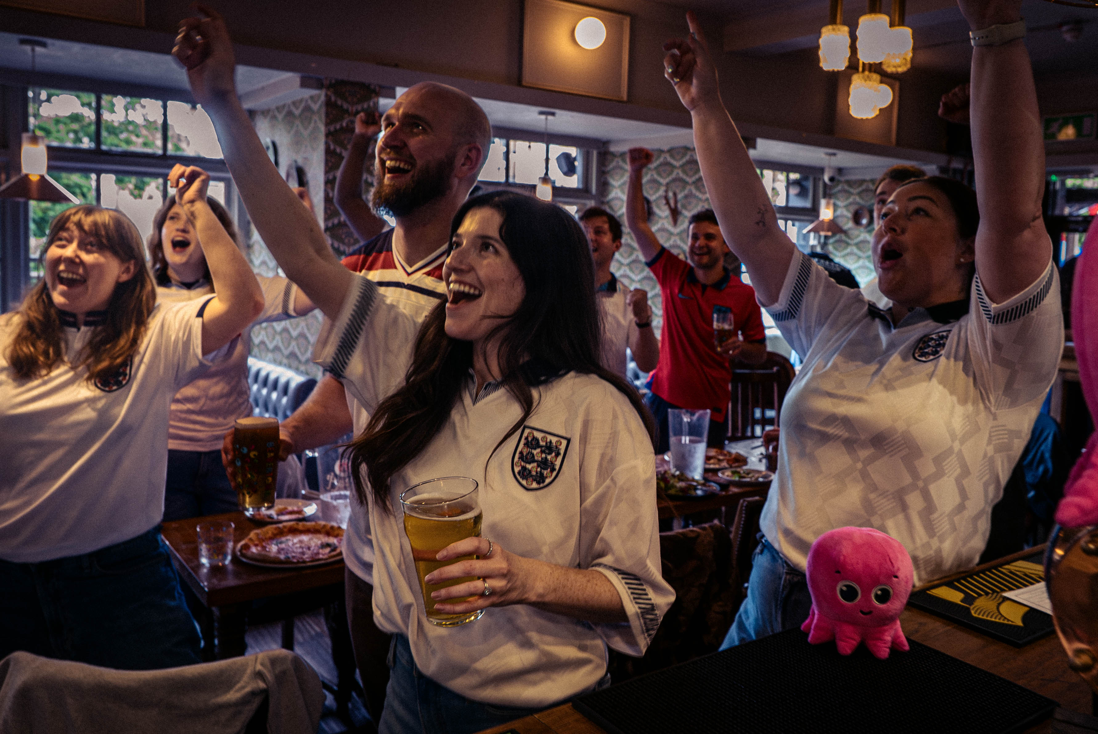 Cheering fans in a pub wearing England football shirts