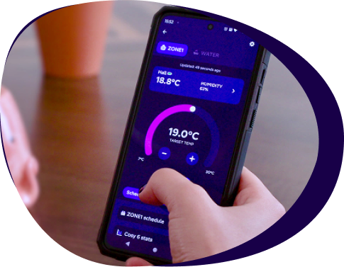 Hand holding a smartphone displaying a temperature control app, showing current and target temperatures with settings options.