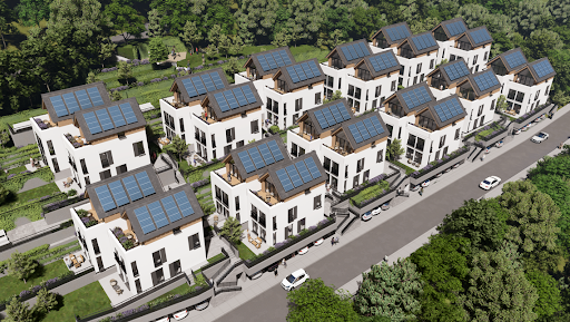 A cluster of modern white houses with solar panels on rooftops, situated along a road in a lush, green, wooded area.