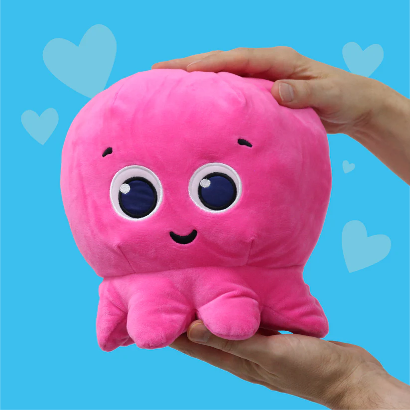Hands holding a cute pink octopus soft toy