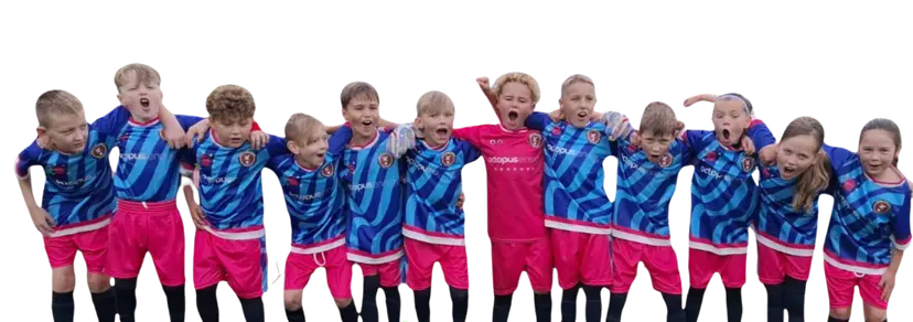 A youth soccer team in blue and pink uniforms stands enthusiastically in a line, arms around each other, posing together.