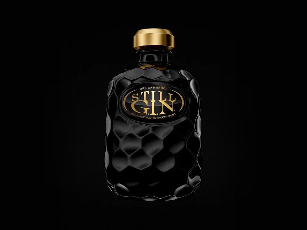 Dark glass bottle of 'Still Gin' with a honeycomb pattern and a gold cap, set against a black background.
