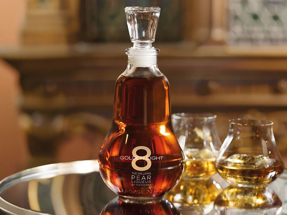 Custom-designed spirits bottle with a pear distinctive silhouette, displayed in an elegant setting with glasses of amber spirits.
