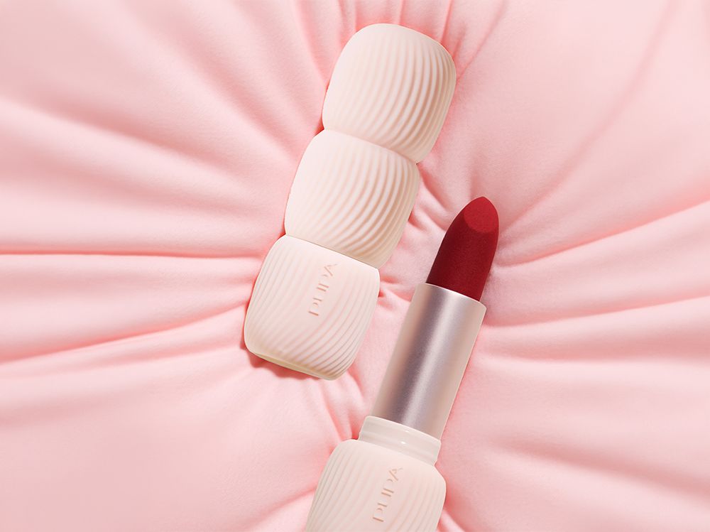 Pupa Milano My Crush lipstick packaging with textured ribbed case and open lipstick in red shade, placed on soft pink fabric background, highlighting cosmetic packaging design and material textures.