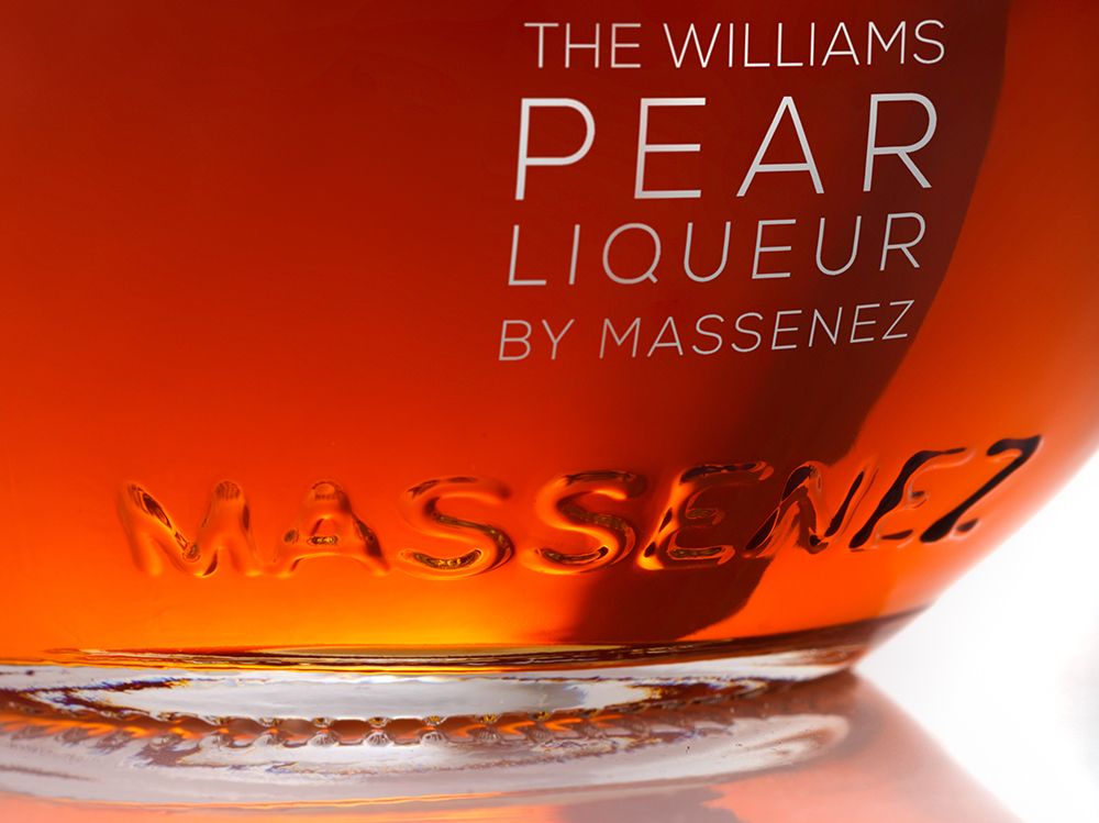 Close-up of a custom-designed spirits bottle with embossed branding and a warm amber glow.